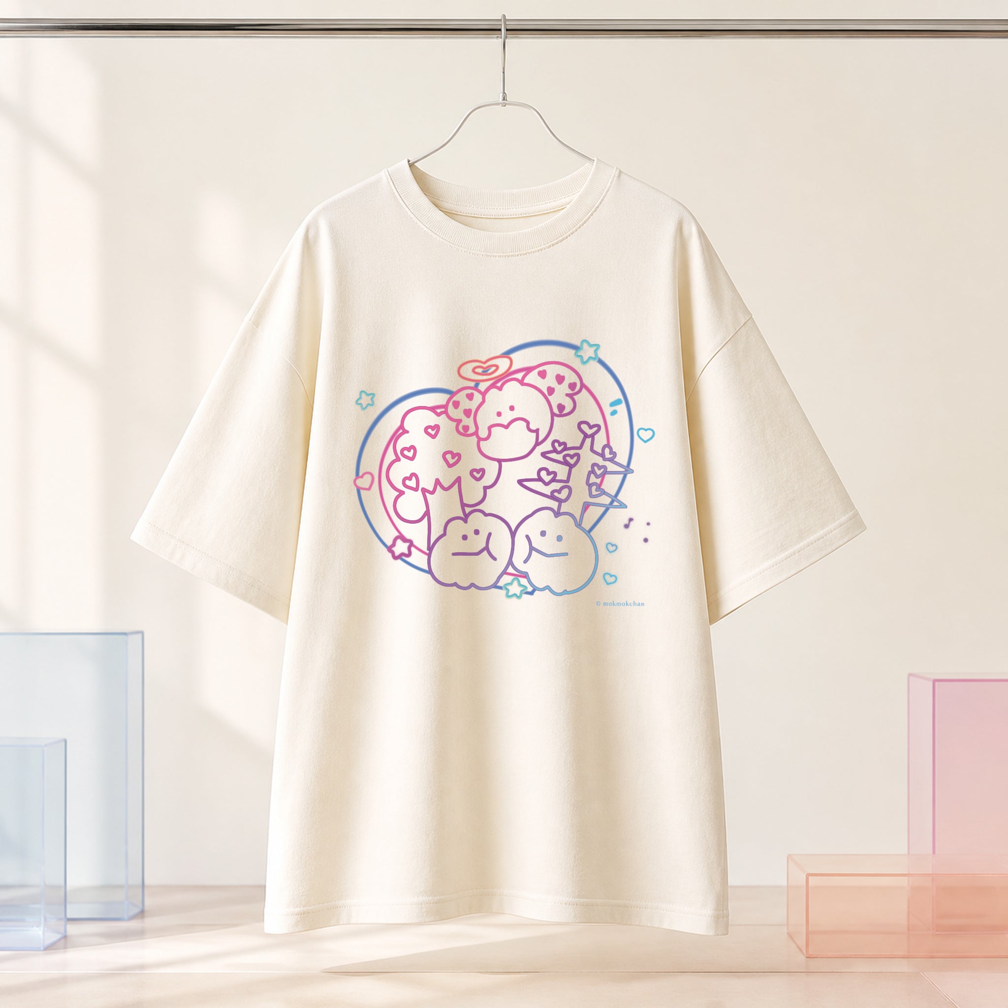 もくもくちゃんのパステル柄をプリントしたアイボリーのオーバーサイズTシャツを、ハンガーで見せた商品画像。