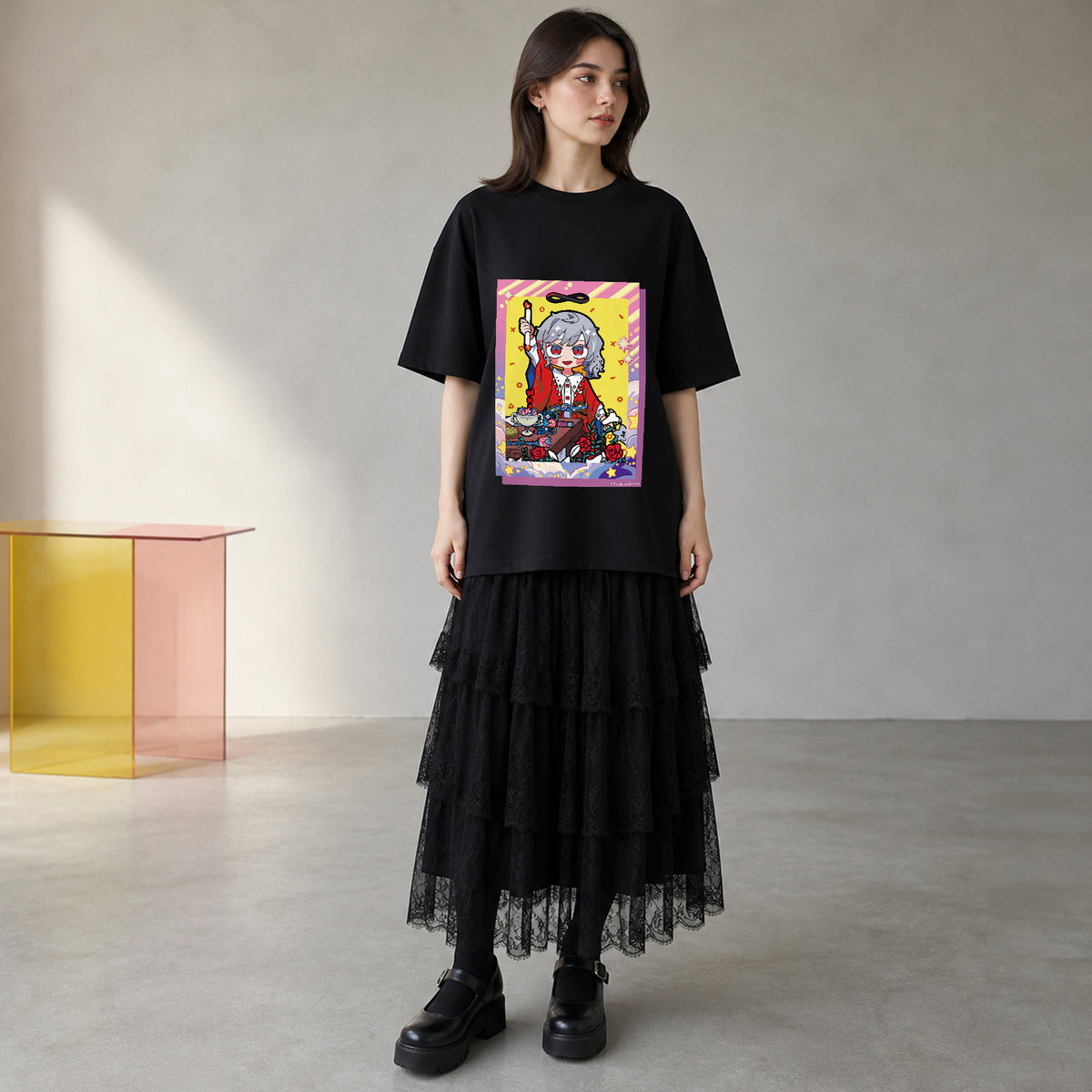 THE MAGICIAN柄をプリントした黒のオーバーサイズTシャツを、若い女性がロングスカートと合わせた着用画像。